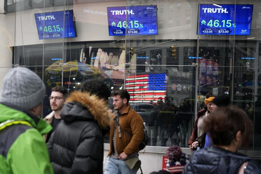 FILE - Pedestrians walk past the Nasdaq building as the stock price of Trump Media & Technology Group Corp. is displayed on screens, March 26, 2024, in New York. On Friday, May 3, Trump Media and Technology Group, the owner of social networking site Truth Social, fired BF Borgers, an auditor that federal regulators recently charged with “massive fraud.” (AP Photo/Frank Franklin II, File)