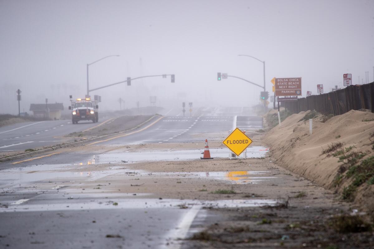 A Caltrans worker patrols with a view of both sides of the closed Pacific Coast Highway in Huntington Beach, due to flooding.