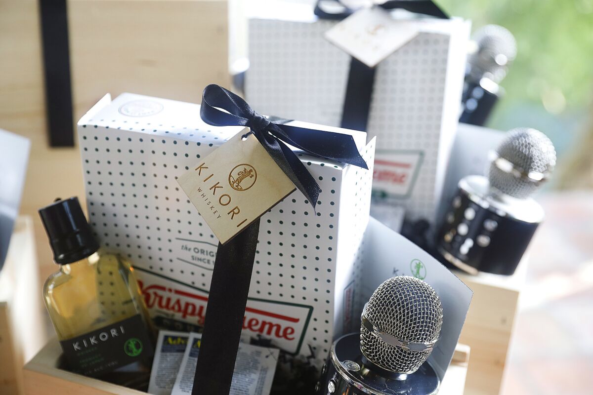 Parting gift boxes of Krispy Kreme donuts, packets of Advil, a bottle of Kikori whiskey, a handheld karaoke mic, and a karaoke song list on a magnet, at the home of Ann Soh Woods.