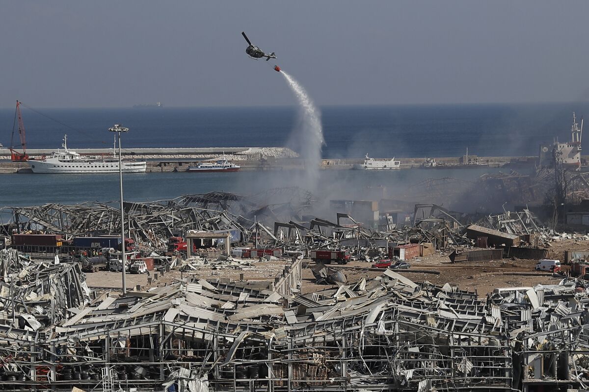 An army helicopter drops water at the scene of Tuesday's massive explosion that hit the seaport of Beirut, Lebanon, Wednesday, Aug. 5, 2020. Residents of Beirut awoke to a scene of utter devastation on Wednesday, a day after a massive explosion at the port sent shock waves across the Lebanese capital, killing dozens of people and wounding thousands. (AP Photo/Hussein Malla)