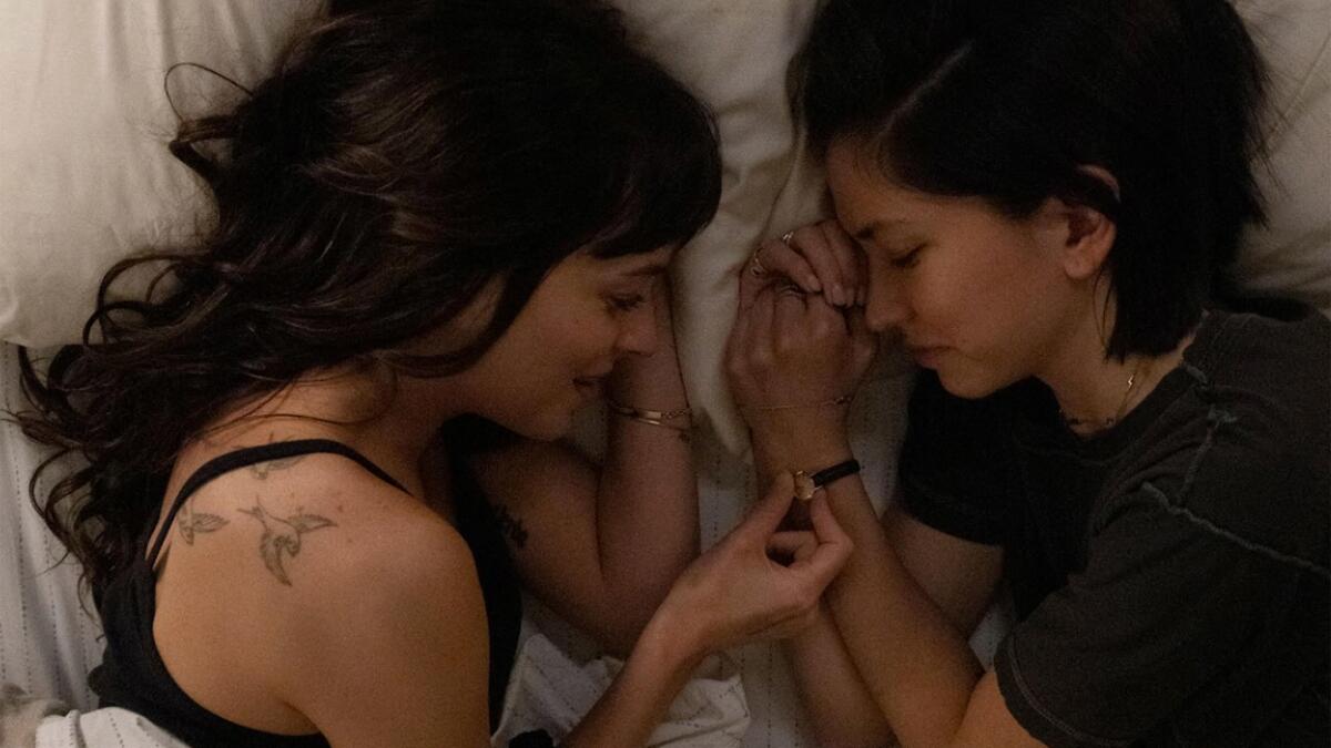 Dakota Johnson and Sonoya Mizuno talk to each other while in bed in a scene from 'Am I Ok?"