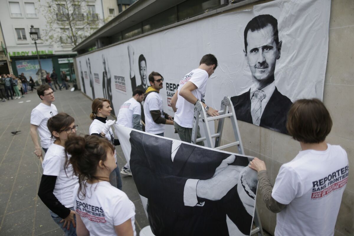 Activists from Reporters Without Borders hang a poster of Syrian President Bashar Assad in Paris to mark World Press Freedom Day.