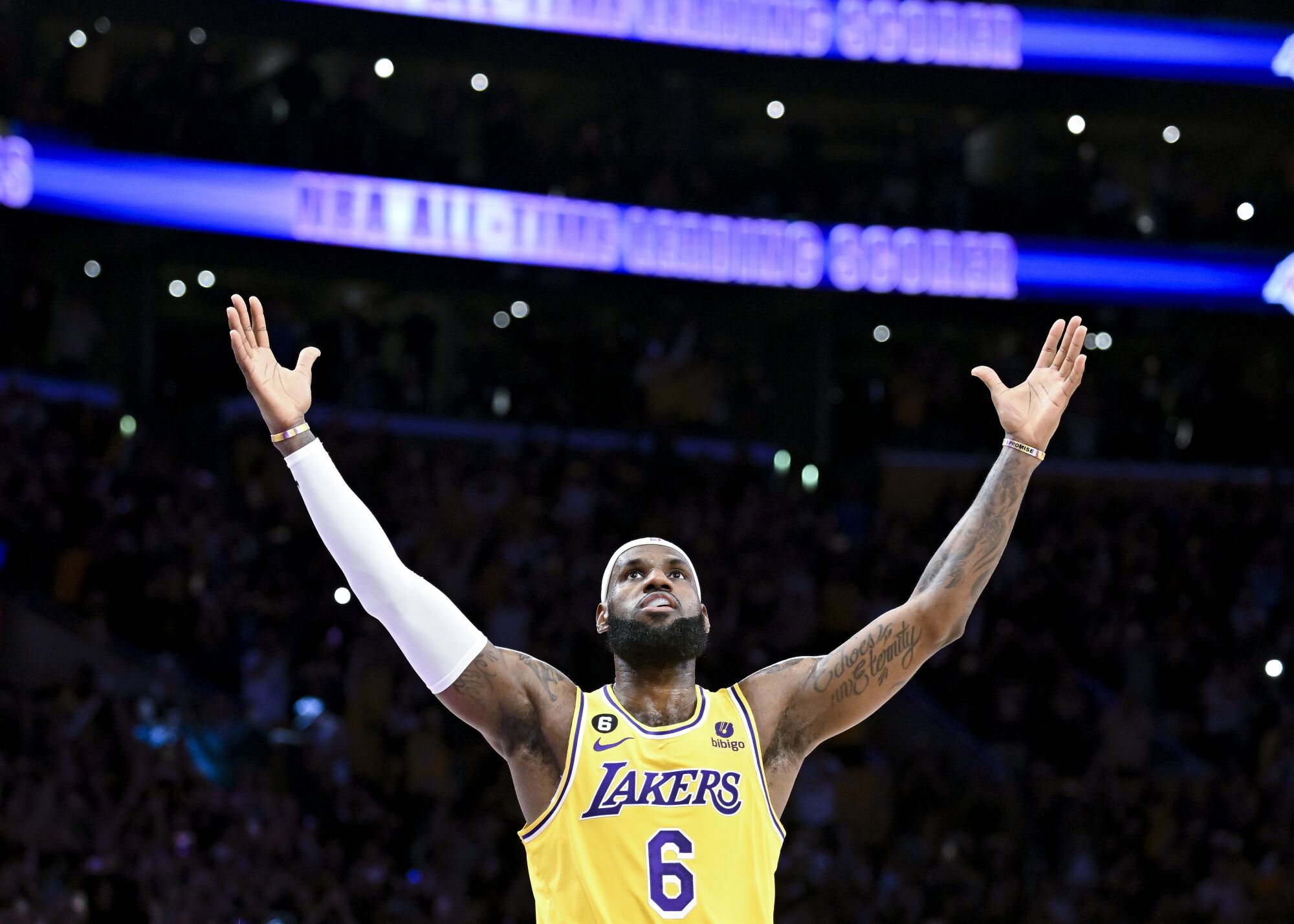 LeBron James raises his arms wide in celebration, looking upward.