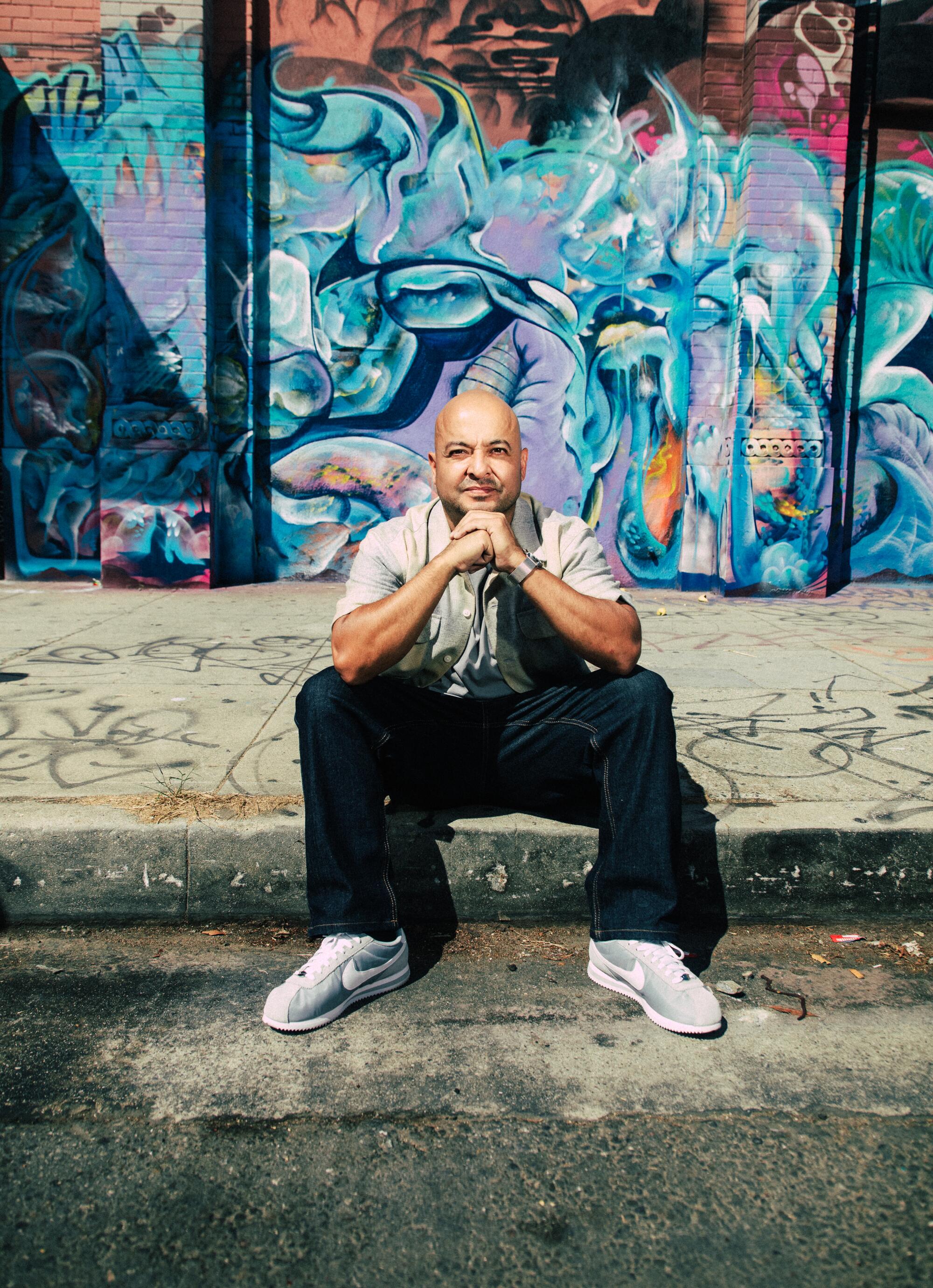 Man sitting on the curb in front of graffiti wall