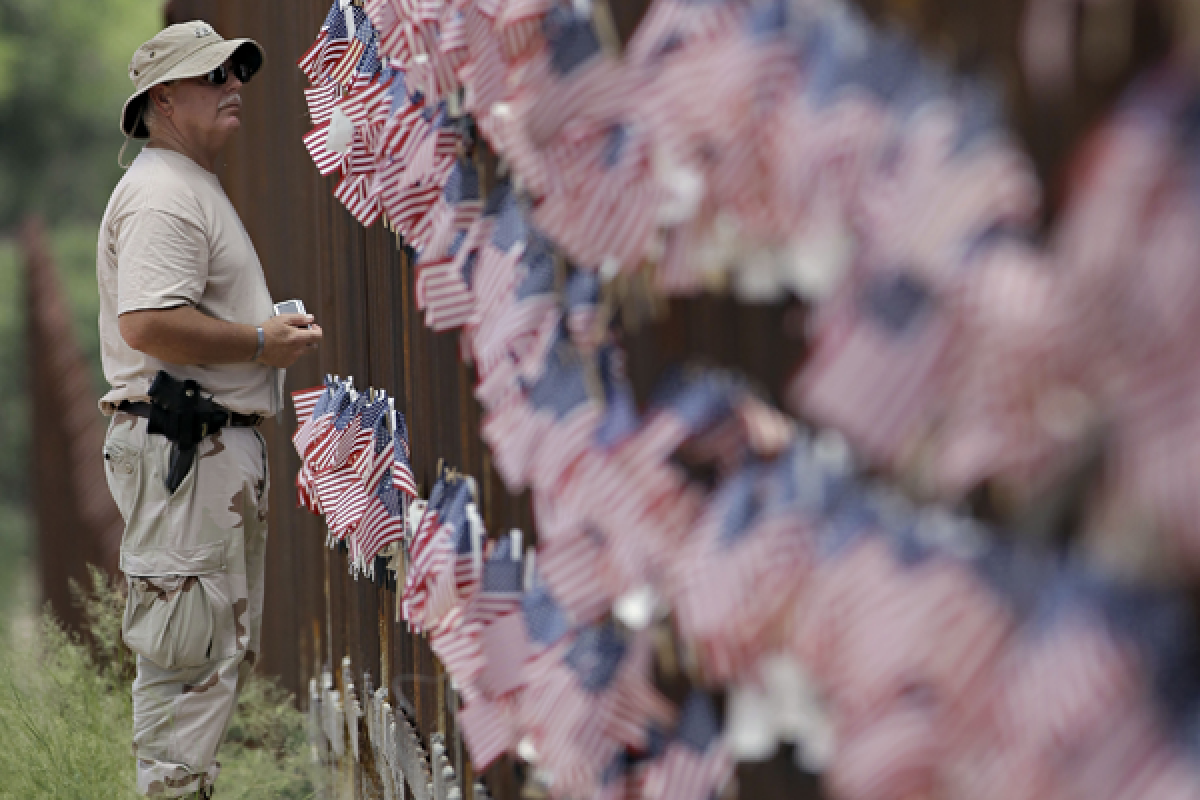 Richard Loomis Jr., of Yarmouth, Maine, looks at the flags hanging on the International border wall in Hereford, Ariz. where tea party groups converged to show support for Arizona's controversial immigration law.