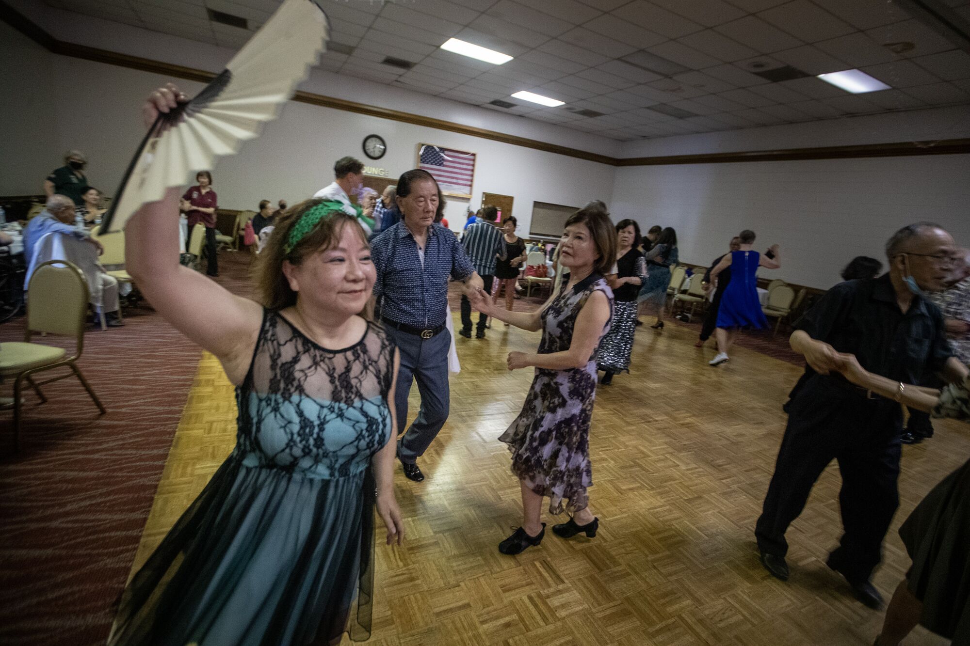 A woman raises a fan while dancing