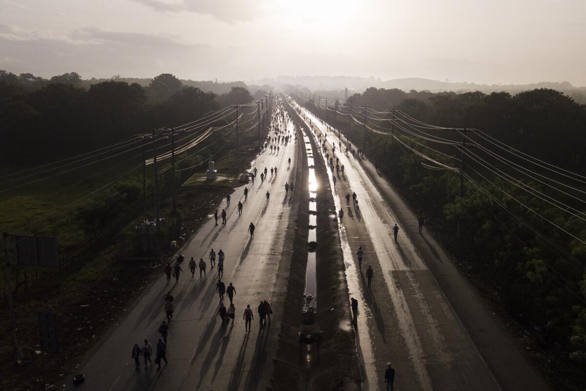 Commuters walk along the Pan American Highway due to roadblocks set up by protesters demonstrating against inflation, especially surging fuel prices, in Pacora, Panama, early Wednesday, July 20, 2022. (AP Photo/Arnulfo Franco)