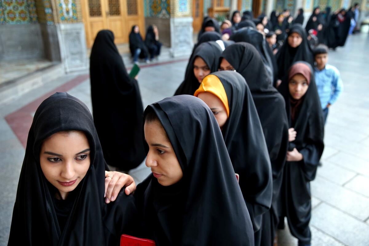 Iranian women stand in line at a polling station during national elections in Qom, Iran.
