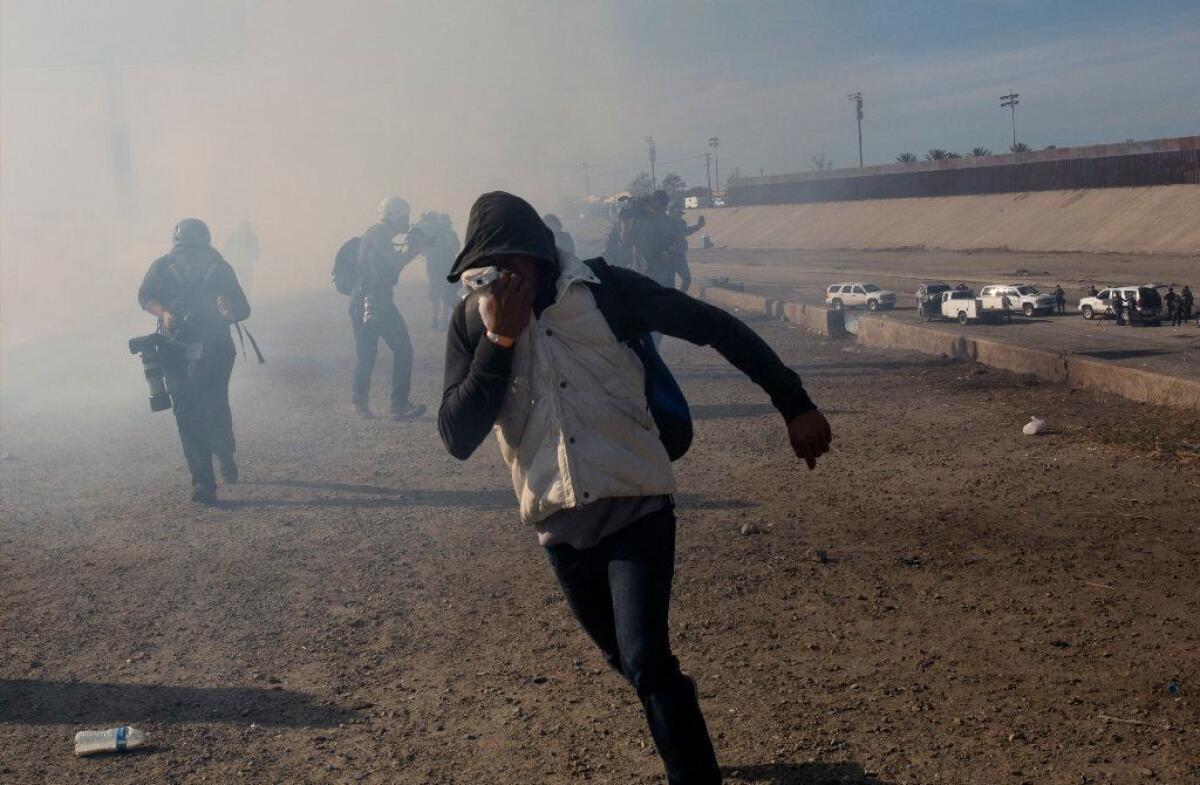 A migrant runs from tear gas launched by U.S. border agents near the the San Ysidro port of entry south of San Diego on Nov. 25.