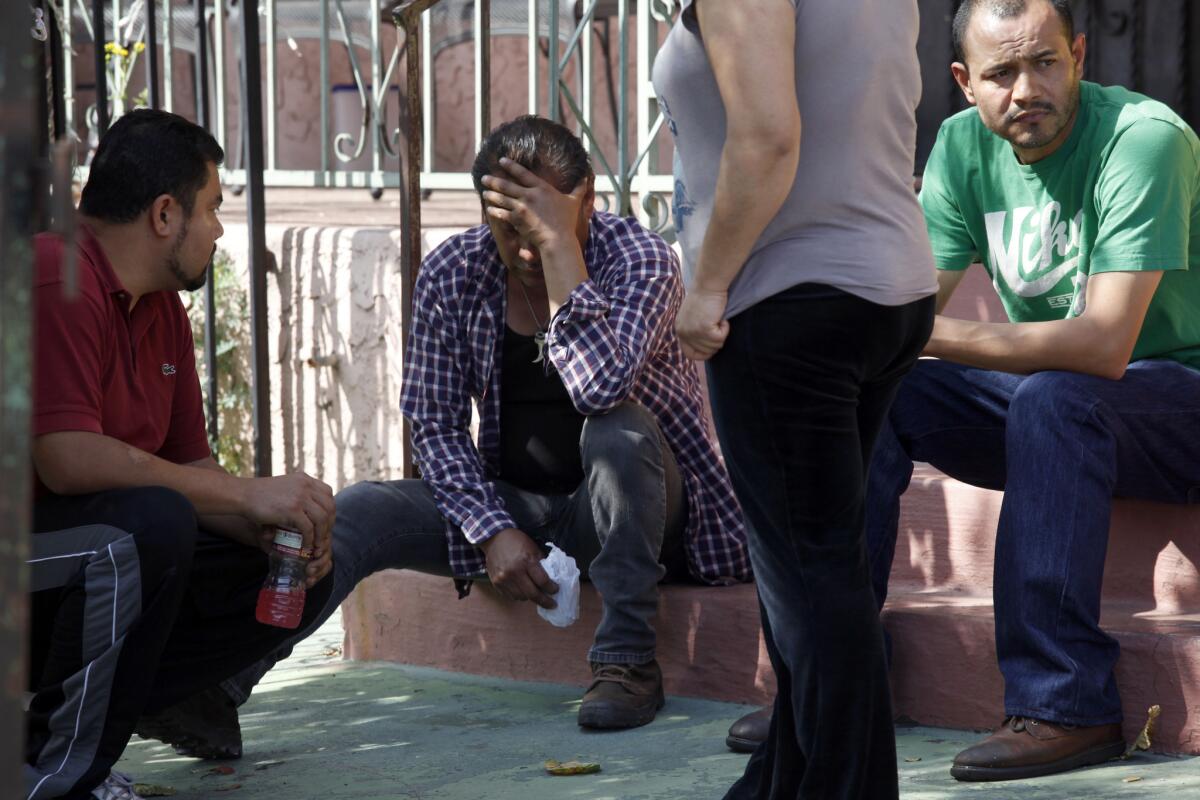 Relatives of the deceased sit outside the residence where a 2-year-old and a woman died in a fire in South Los Angeles.