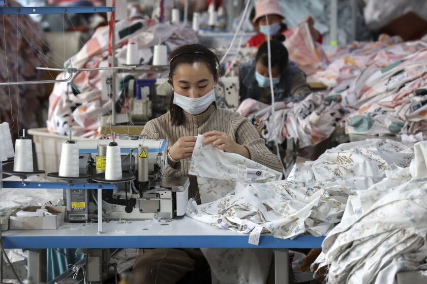 FILE - Workers wearing face masks sew fabrics at a textile factory in Huimin county in east China's Shandong province on Oct. 25, 2022. Chinese factory activity rebounded in January from three months of contraction, adding to signs the world’s second-largest economy might be recovering from a painful slump, an official survey showed Tuesday, Jan. 31, 2023. (Chinatopix Via AP, File)
