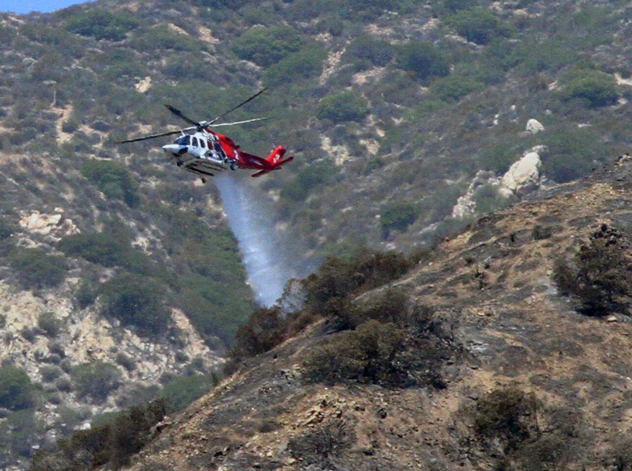 A Los Angeles Fire Department helicopter drops water on a hot spot in the Verdugo Mountains where the a brushfire, that started yesterday, continues to burn on Monday, June 23, 2014. The fire is above Brand Park, and hasn't threatened any structures.