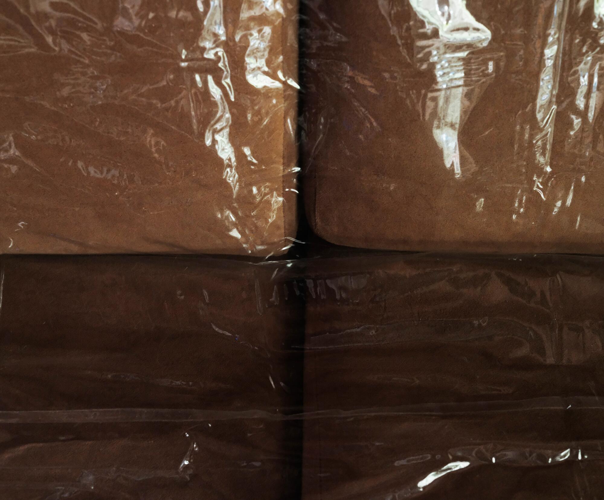 A close-up photo of a plastic-covered brown couch.