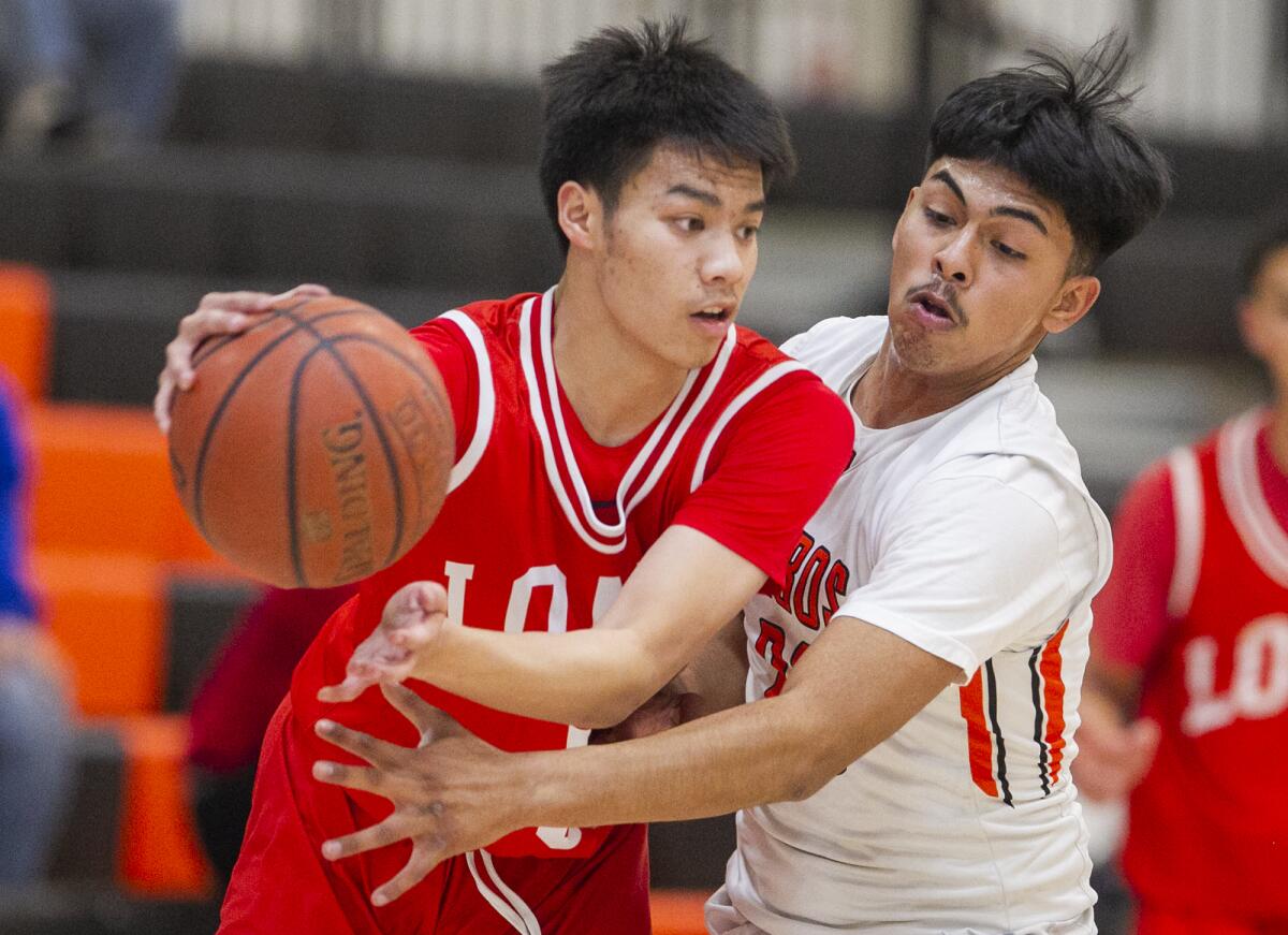 Los Amigos' Brian Pacheco, right, shown guarding Loara's Tyler Nanthavong on Feb. 4, helped the Lobos win the Garden Grove League title.