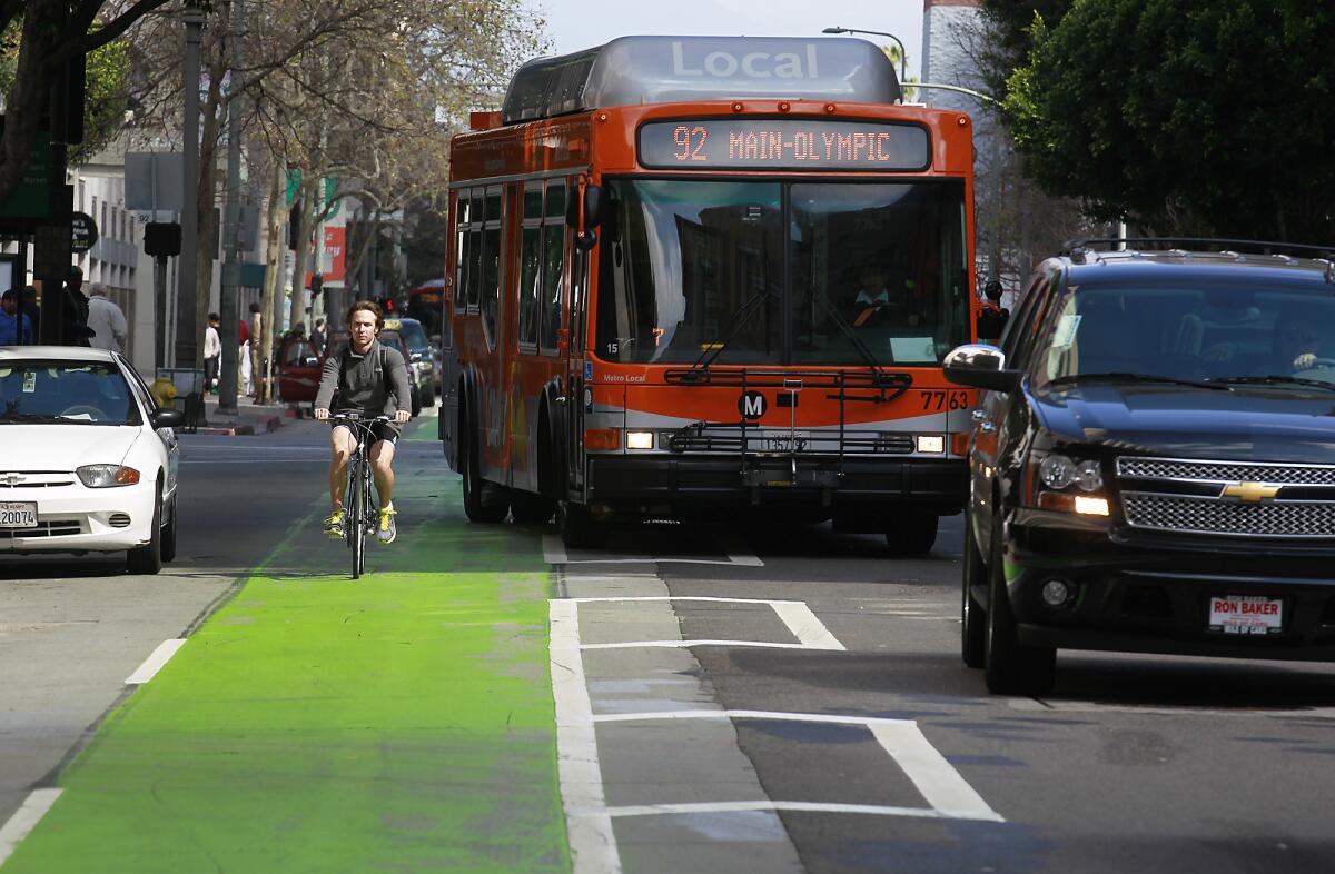 Film crews work on the show "Ringer" as cyclists, cars and buses pass in the green bike lane in the 400 block Spring Street last year. City officials approved a plan Wednesday that would replace the bright color with a forest green that is less visible on film.