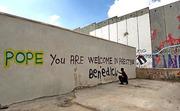 A Palestinian boy writes a welcome message to Pope Benedict XVI on a section of Israel's separation barrier next to the Aida refugee camp in the West Bank town of Bethlehem.
