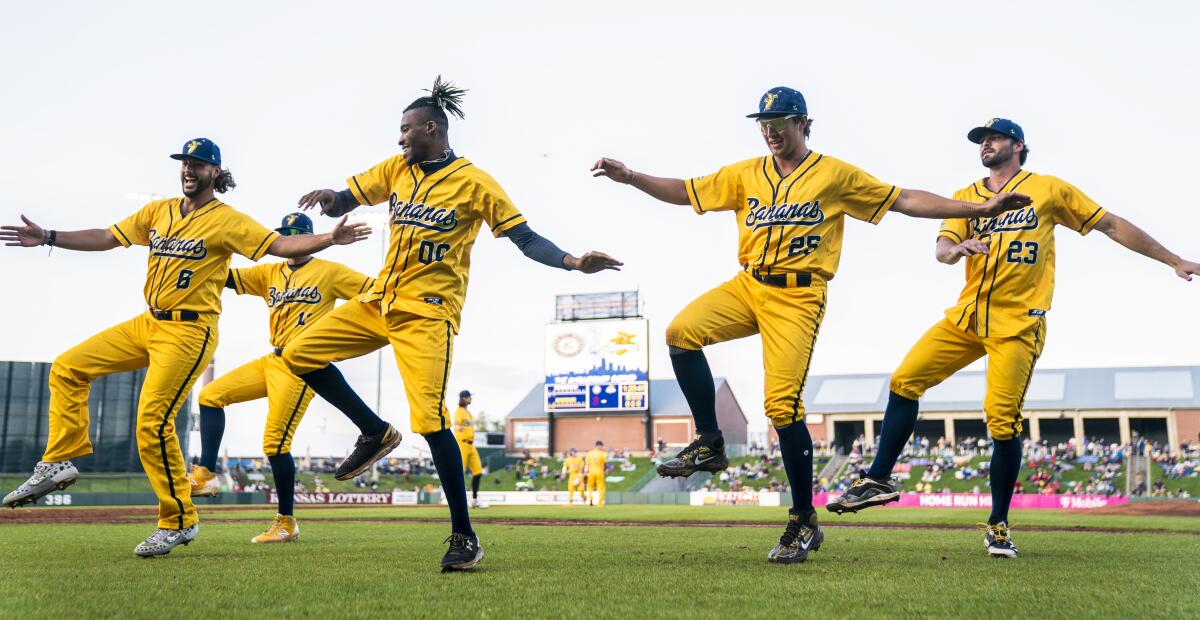 Savannah Bananas first base coach Maceo Harrison (00) dances with players during a game.