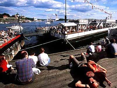 Soaking up northern sunshine and summer scenery--and for some, it's a food feast alfresco--on Aker Pier in Oslo. Norway's lively, cosmopolitan capital city is at the head of the 60-mile Oslo Fiord.