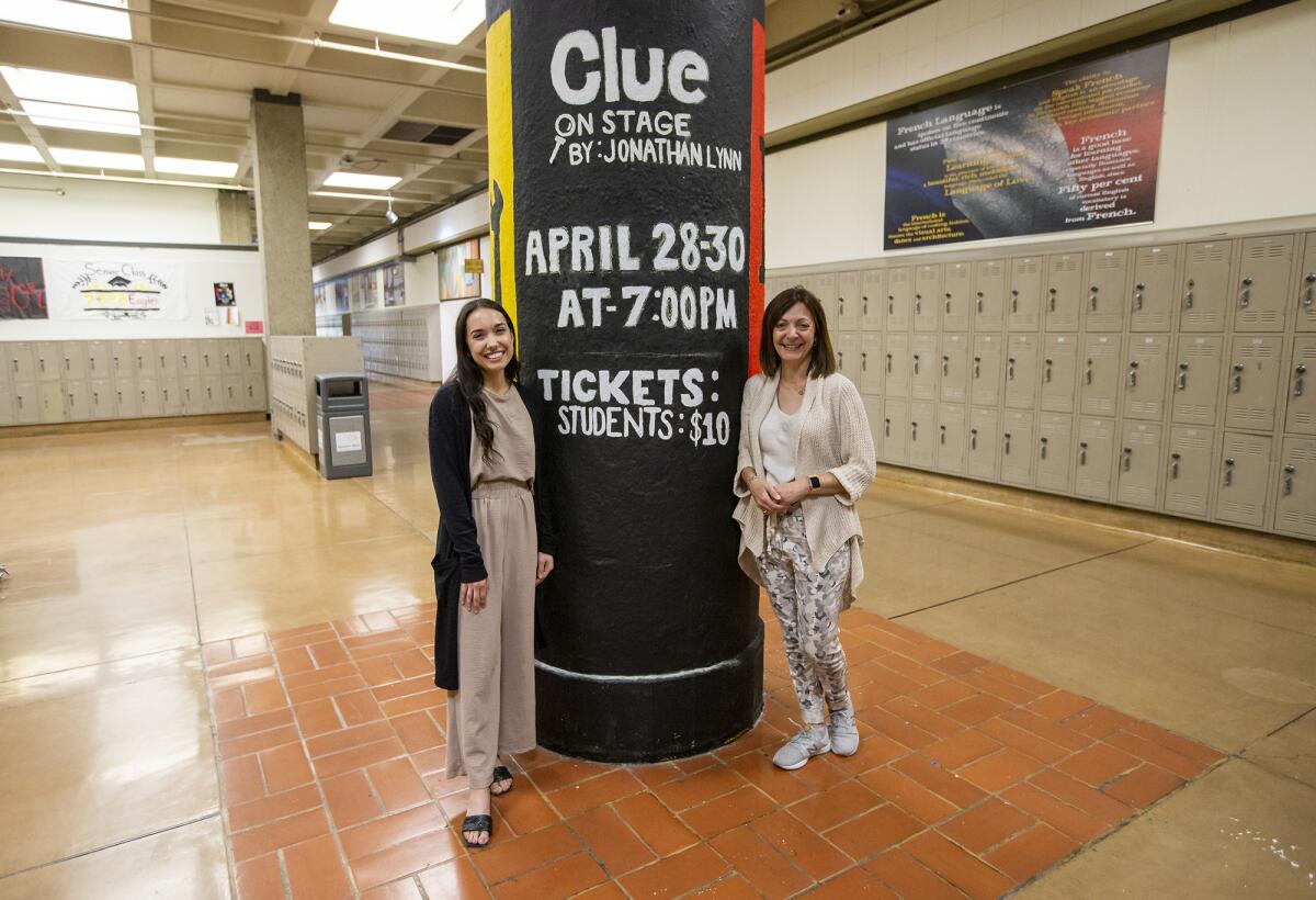 Student teacher Amber Marroquin, left, and Pauline Maranian near a pole advertising the upcoming production of "Clue."