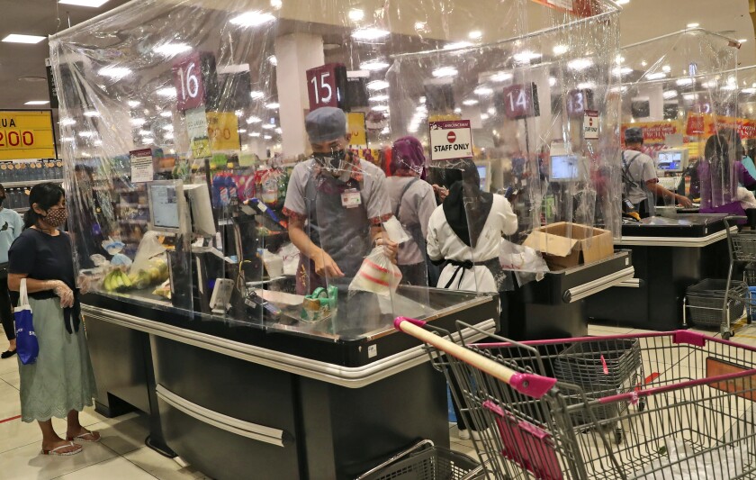 Cashiers serve customers from behind plastic sheets at a mall outside Jakarta, Indonesia, in May.