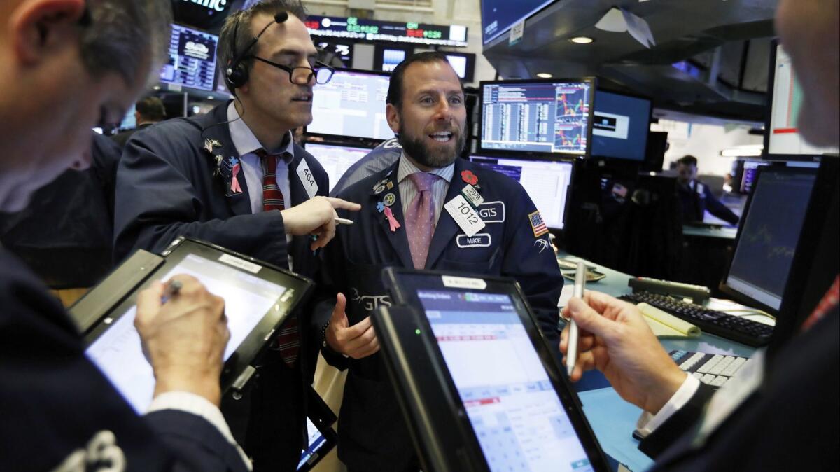 Specialist Michael Pistillo center, works with traders at his post on the floor of the New York Stock Exchange this month.