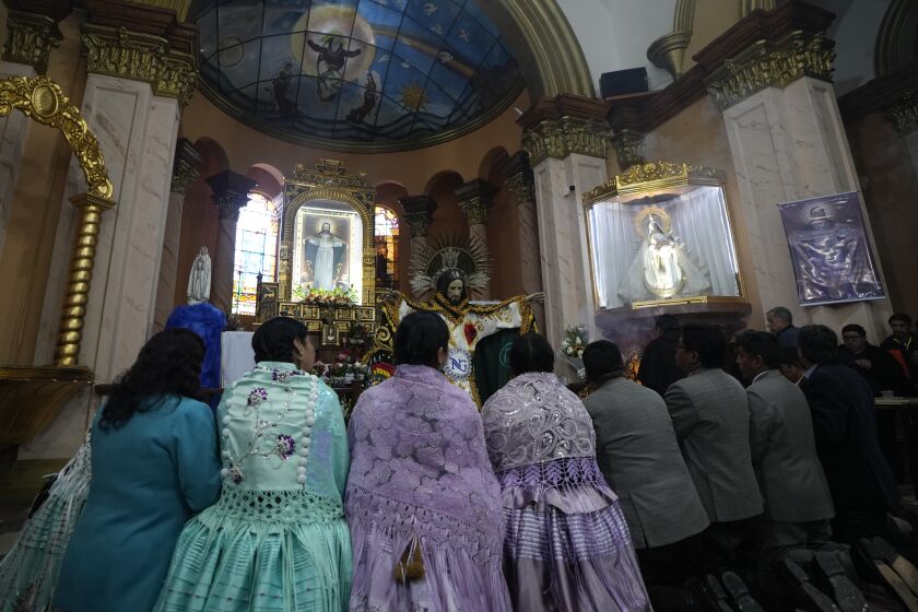 Devotos rezan después de vestir la estatua de Jesús del Gran Poder en la iglesia Jesús del Gran Poder en La Paz, Bolivia, el jueves 1 de junio de 2023. (AP Foto/Juan Karita)