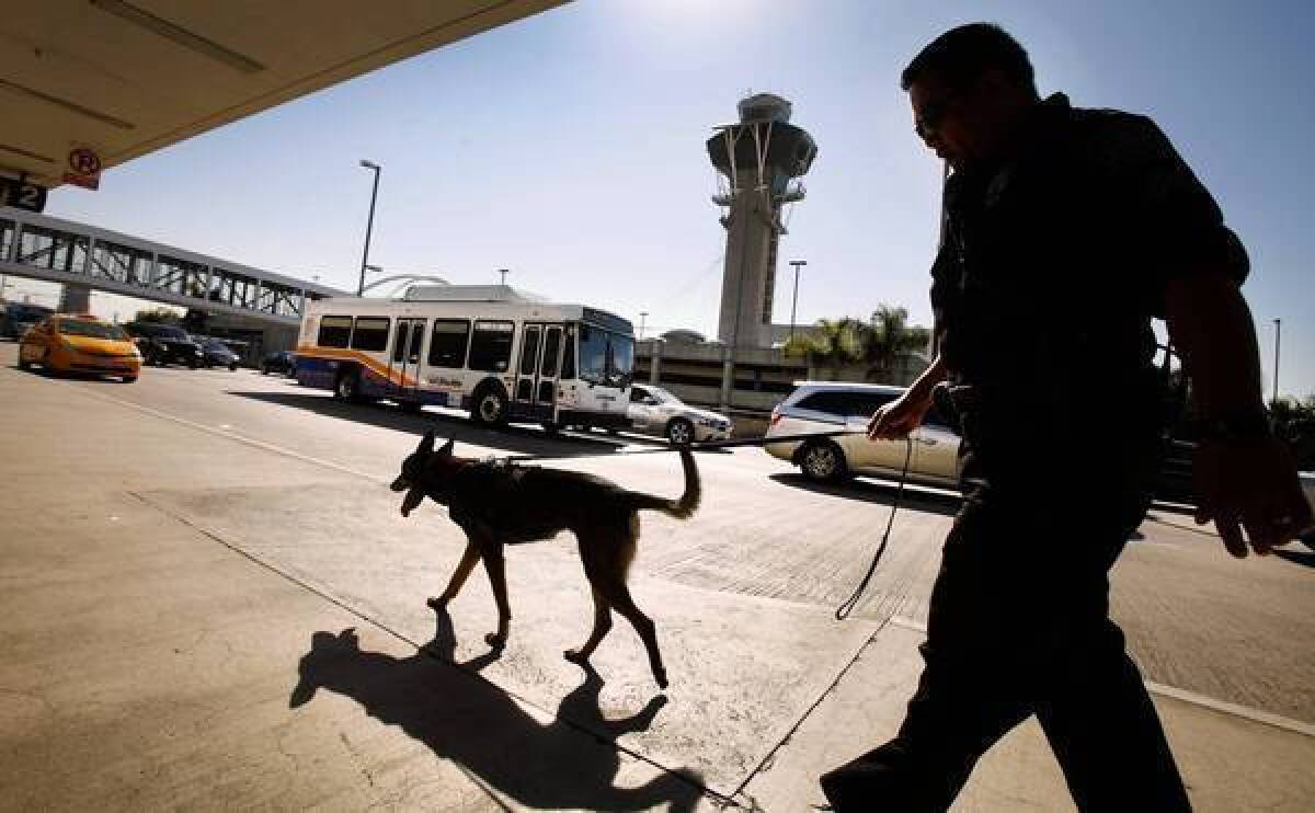Los Angeles Airport Police Officer Orlanes with bomb sniffing dog walks through Terminal 2 on Tuesday morning after the latest bottle with dry ice exploded about 8:30 p.m. Monday.