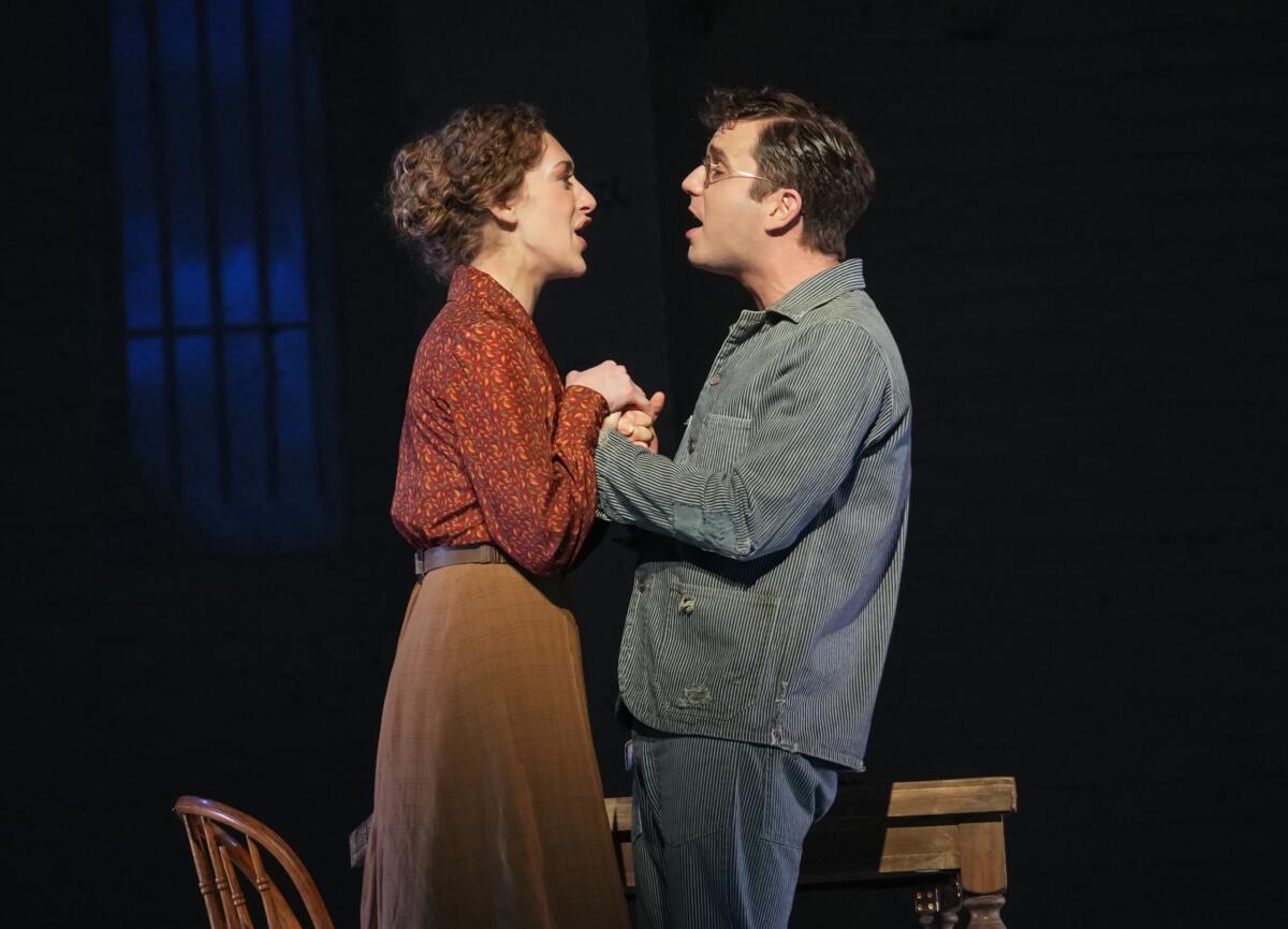 An actress and actor in period dress clutch hands while singing to each other in "Parade" at the Bernard B. Jacobs Theatre. 