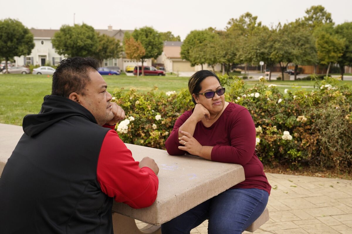 Makerita Iosefo-Va'a and her husband Shaun Va'a sit together in a park near a relative's home where they are temporarily staying in Tracy, Calif., on Oct. 8, 2020. The couple are homesick for American Samoa. She's among an estimated 600 residents of the U.S. territory who were away when American Samoa's governor closed borders to keep the cluster of Pacific islands free from coronavirus. Vaʻa and others say they don't want American Samoa to open its borders, but just to bring them home safely. (AP Photo/Eric Risberg)