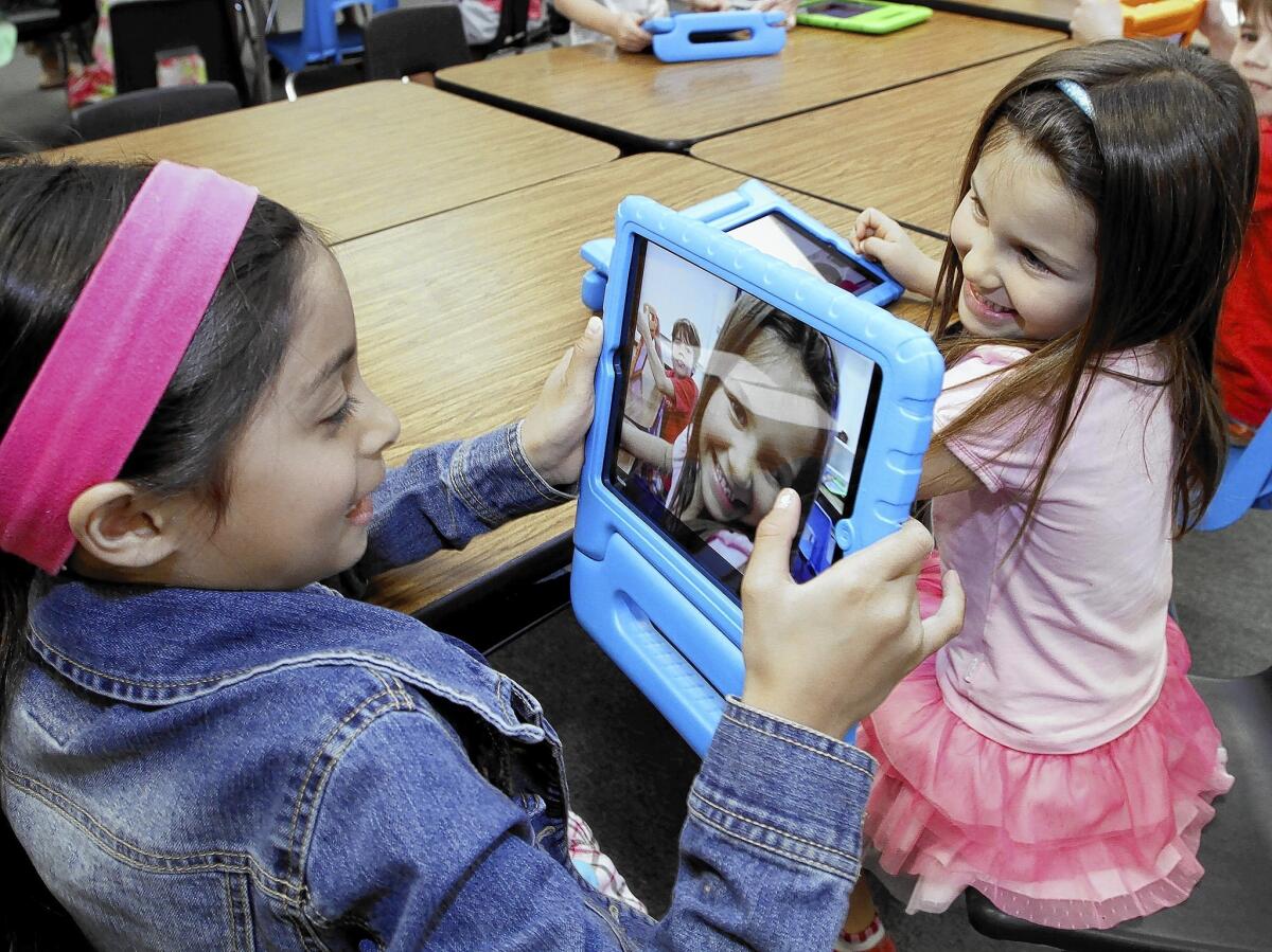 First grader Lexi Frost, left, takes a photo of her friend Kate Cooper, right, during class at Palm Crest Elementary School's iPad Learning Lab in La Cañada Flintridge on Tuesday, April 8, 2014. The school district recently opened three elementary school iPad Learning Labs with donations from the Educational Foundation.