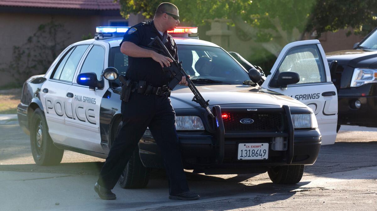 Palm Springs police officers search for a suspect on Bahada Road after three Palm Springs officers were shot, two of whom were killed.