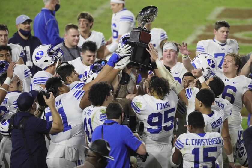 BYU players hold the championship trophy after defeating UCF in the Boca Raton Bowl NCAA college football game at FAU Stadium in Boca Raton, Fla. Tuesday, Dec. 22, 2020.(Al Diaz/Miami Herald via AP)