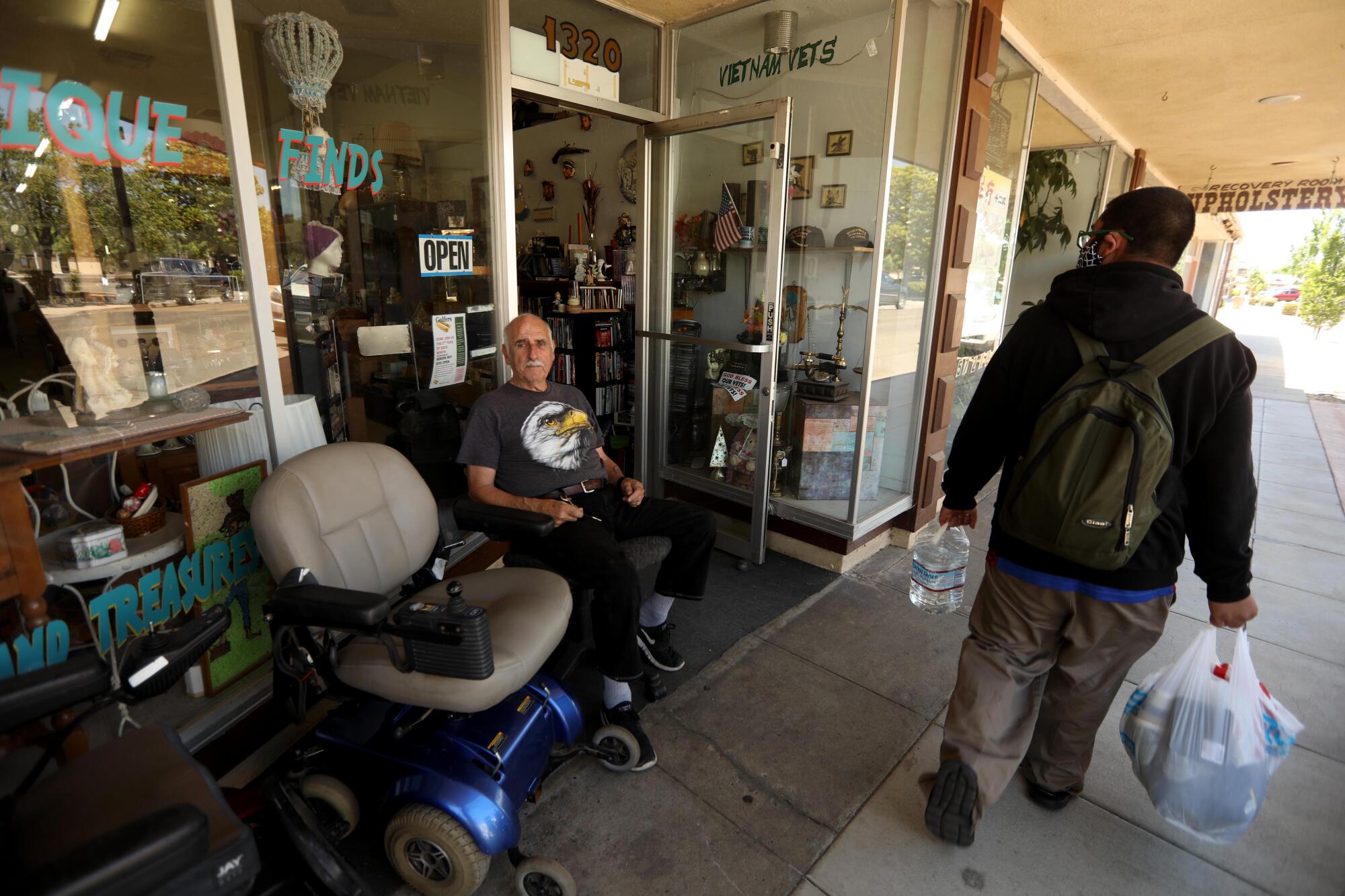 Larrie Long waits for customers in front of Thrift and Treasures in the historic downtown of Atwater