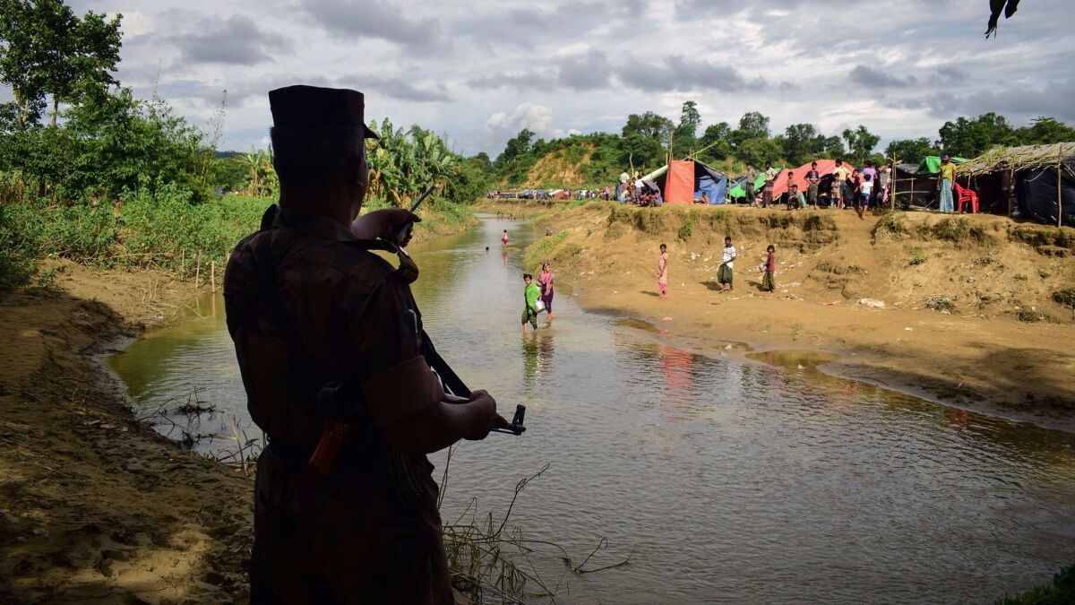A Bangladeshi border guard orders Rohingya refugees to return to the Myanmar side of a small canal between the two countries on Aug. 29, near the Bangladeshi town of Ukhiya.