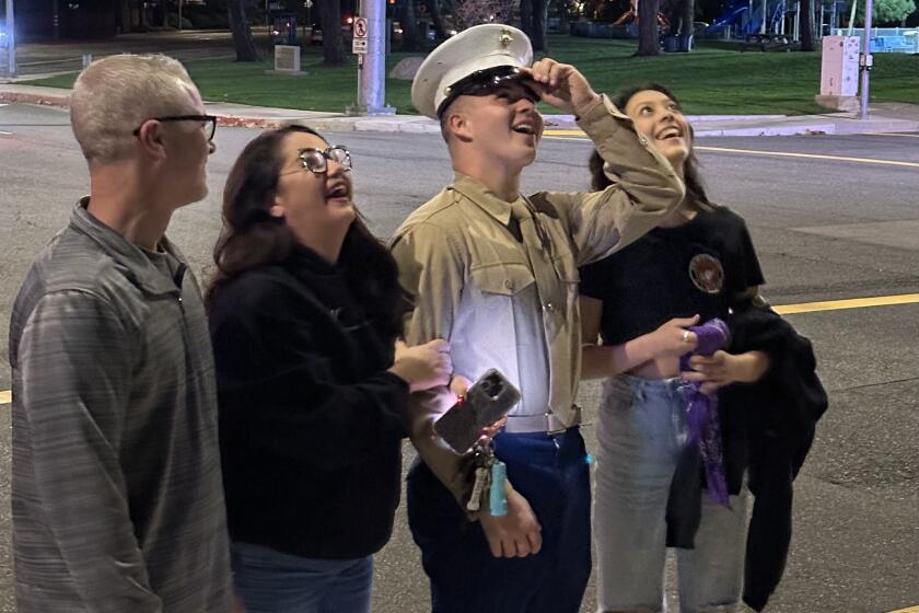 Eric Costelloe, Laura Costelloe, Alexe Pappageorge Jr. and Mariah Tapia look up at the new "hometown hero" banner in Pappageorge's honor on Wednesday night in Huntington Beach.