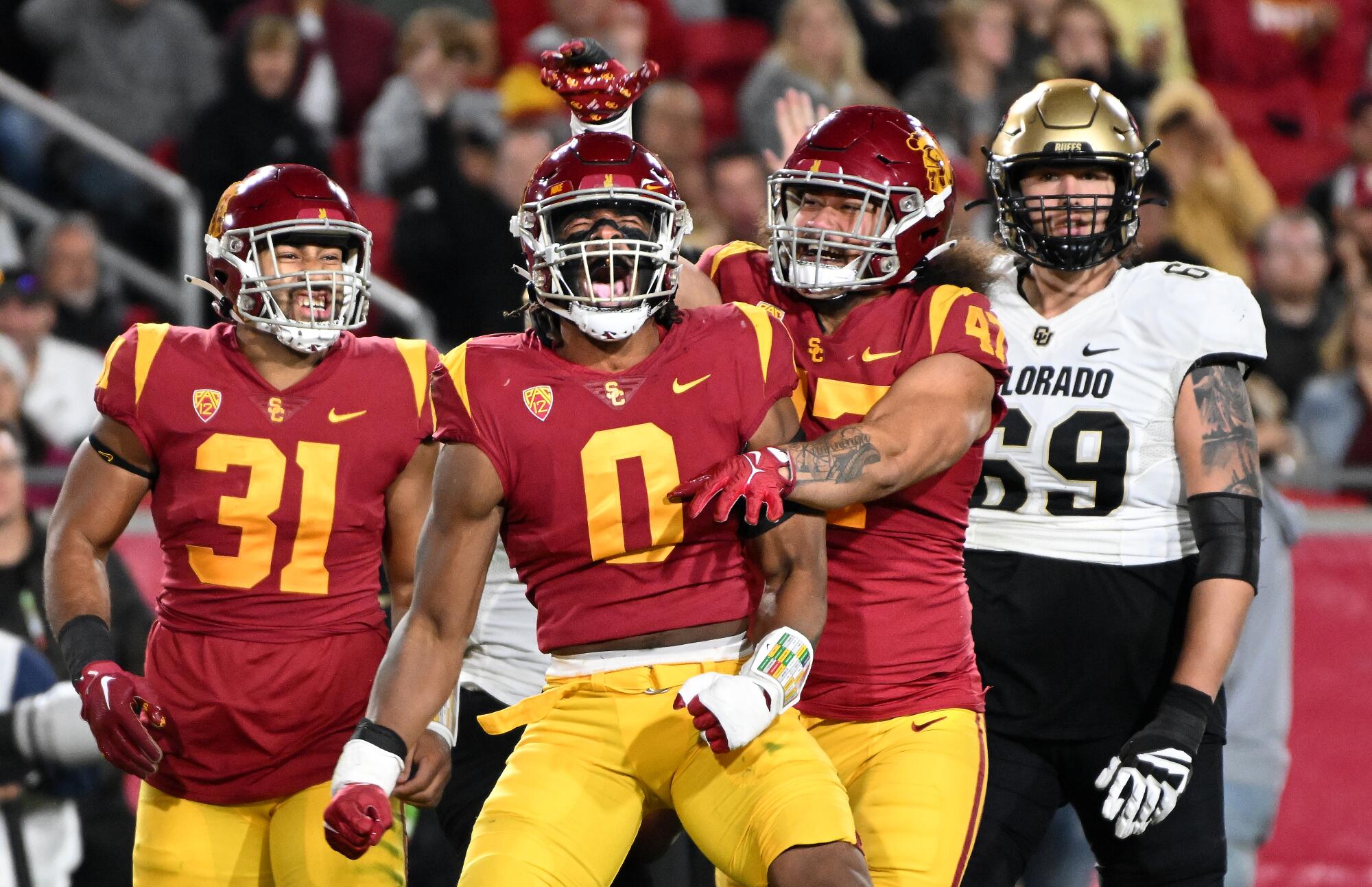 USC's Korey Foreman celebrates his tackle for a loss with Tyrone Talent and Stanley Taufo'ou against Colorado.