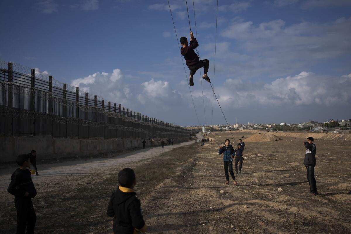A person descends on a rope as others look on from the ground