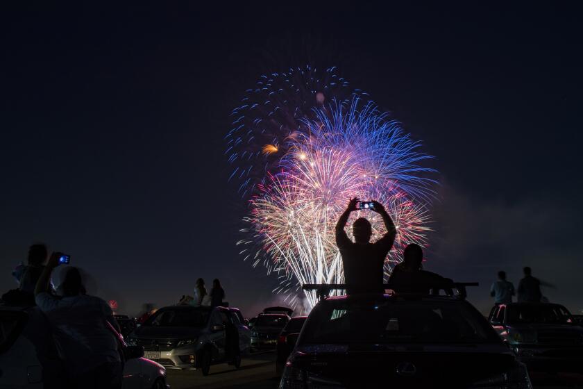 LOS ALAMITOS, CA - JULY 4, 2020: Southern California residents sit on the roofs of their vehicles to watch the fireworks during the Drive-Up 4th of July Spectacular at the Los Alamitos Joint Forces Training Base during the coronavirus pandemic on July 4, 2020 in Los Alamitos, California. (Gina Ferazzi / Los Angeles Times)
