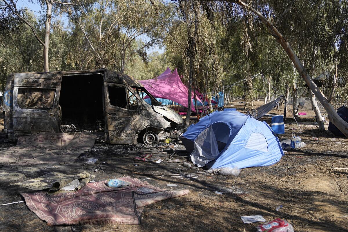 A burned van and tents sit at the site of a music festival after Hamas militants attack inside Israel.