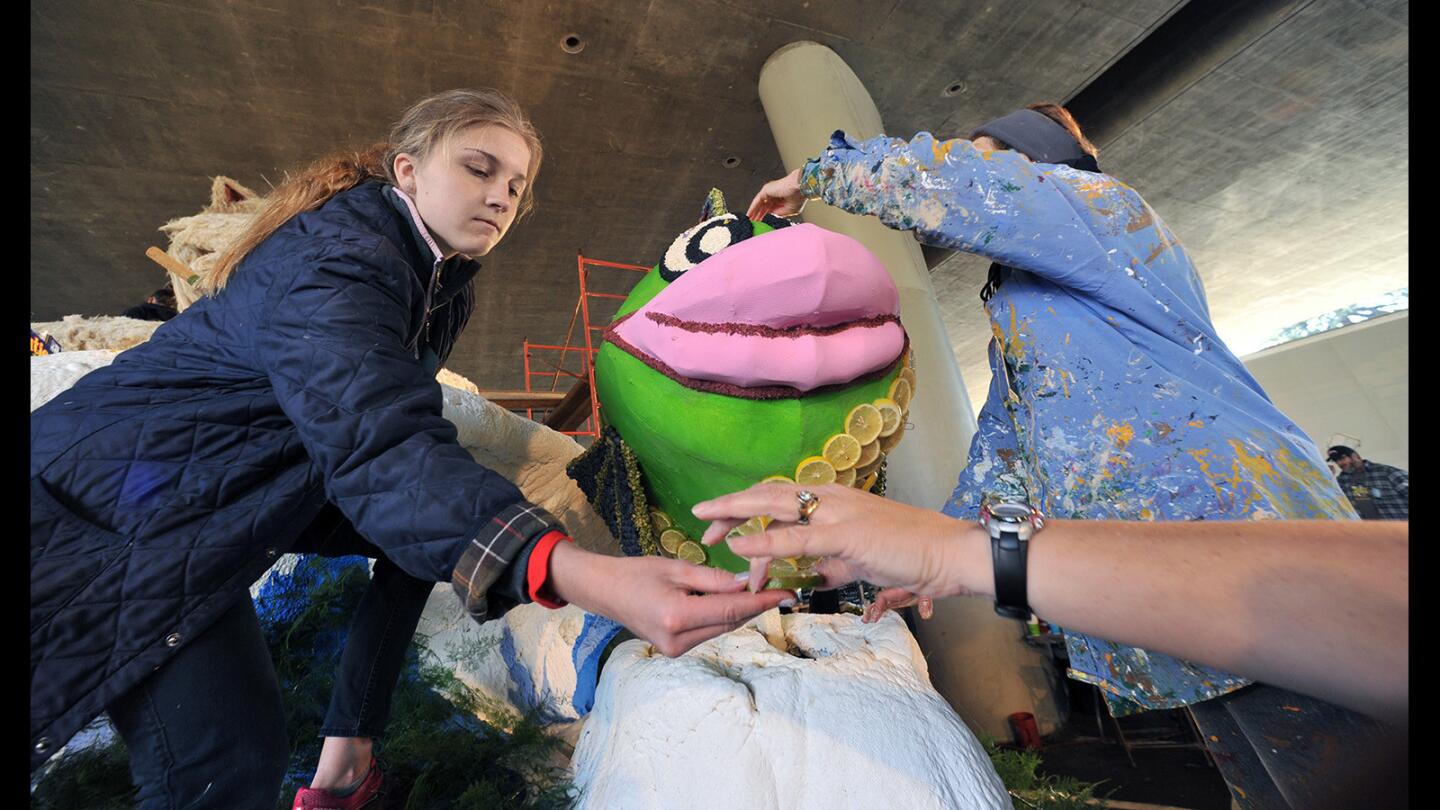 McKenna Smith, 15, reaches for a handful of lemon and lime slices covered in florist glue while Myrna Hershman applies the mixture to the La Cañada Flintridge Rose Parade float on Wednesday, Dec. 30, 2015.