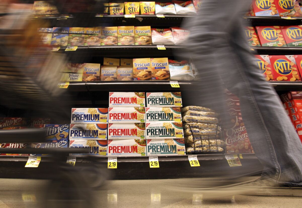 FILE - In this Feb. 9, 2011, photo, a shopper passes Nabisco products, a Mondelez International brand: Premium saltines, Triscuits, Ritz crackers and Wheat Thins, at a supermarket in Los Angeles. Ukrainian President Volodymyr Zelenskyy is stepping up the country's pleas to pressure companies to exit Russia. On Tuesday, March 15, 2022, in an address, Zelenskyy called out food companies Nestle and Mondelez, consumer goods makers Unilever and Johnson & Johnson, and European banks Raiffeisen and Societe General, saying they and “dozens of other companies” have not left the Russian market. Companies, in turn, point to the difficulties of ceasing operations. (AP Photo/Reed Saxon, File)