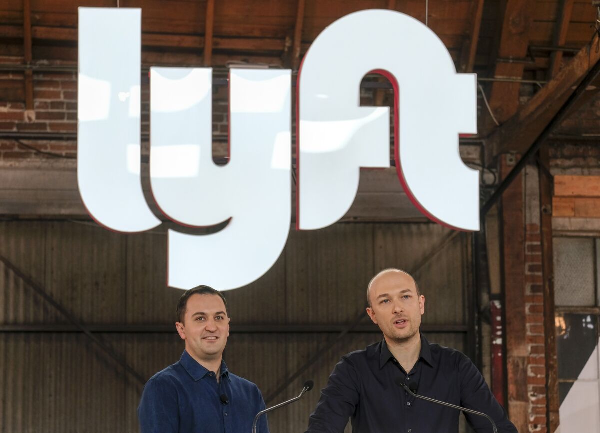 FILE - Lyft co-founders John Zimmer, left, and Logan Green speak before they ring a ceremonial opening bell in Los Angeles on March 29, 2019. The Lyft co-founders are relinquishing their leadership roles in an announcement Monday, March 27, 2023, to make way for a former Amazon executive as the ride-hailing service struggles to recover from the pandemic while long-time rival Uber has been regaining its momentum. (AP Photo/Ringo H.W. Chiu, File)