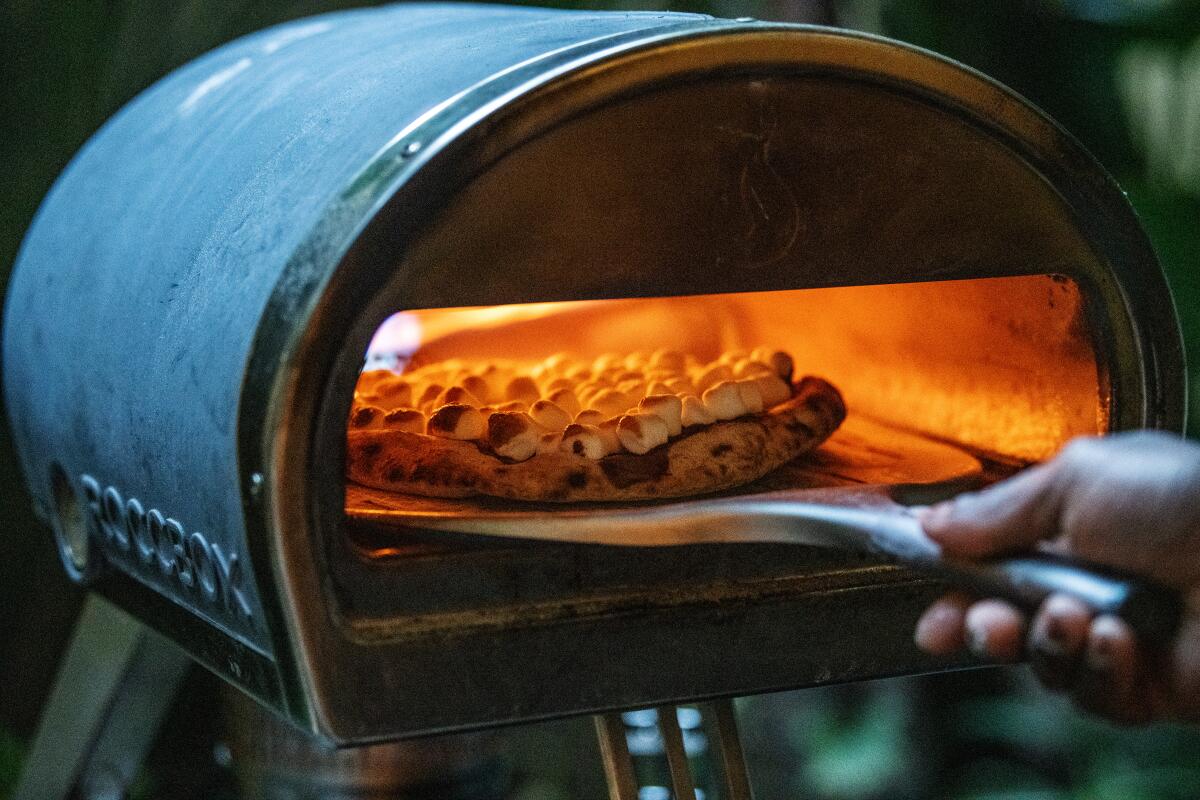 A pizza bakes inside a small pizza oven.