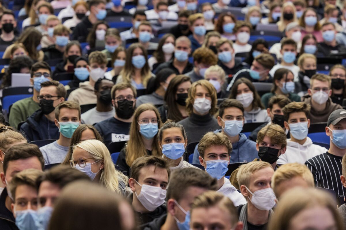 FILE - Students wear mouth-to-nose coverings while sitting close to each other during the lecture 'BWL 1' in lecture hall H1 of the Westfaelische Wilhelms-Universitaet in Muenster, Germany, Wednesday, Oct. 21, 2021. Germany's disease control agency has reported the highest number of new infections with the coronavirus since the outbreak of the pandemic. (Rolf Vennenbernd/dpa via AP)