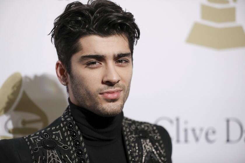 A man with black hair posing in a black turtleneck