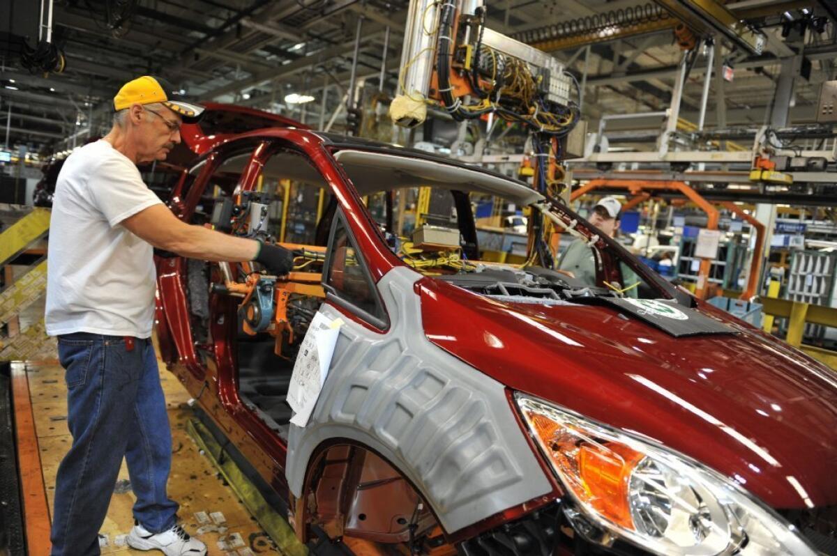 An autoworker installs a dashboard at Ford's Michigan Assembly Plant.