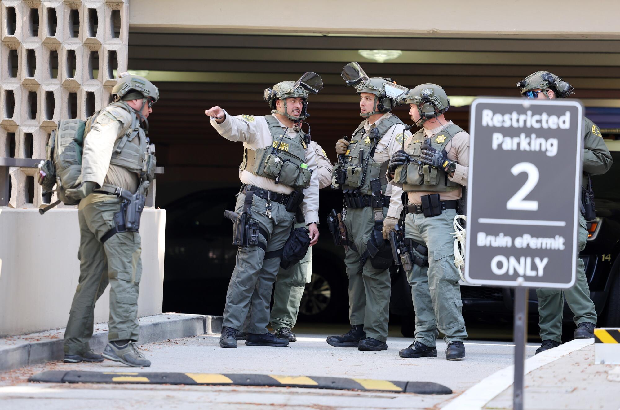 Law enforcement officers stand at a parking garage entrance.