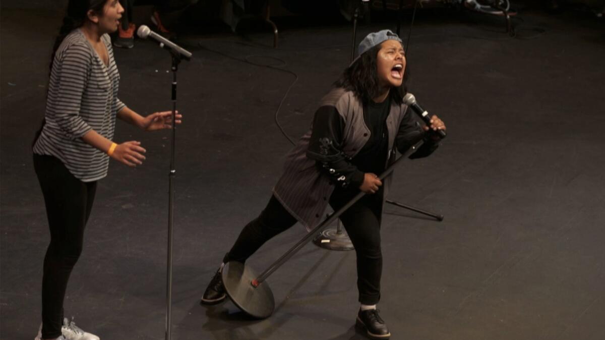 High school senior Vanessa Tahay, right, recites poetry with classmate Amandeep Kaur during the poetry slam competition at the Los Angeles Theater Center.