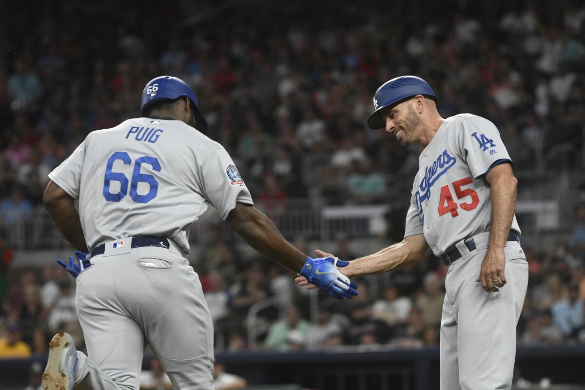 Yasiel Puig, left, is congratulated by Dodgers third base coach Chris Woodward