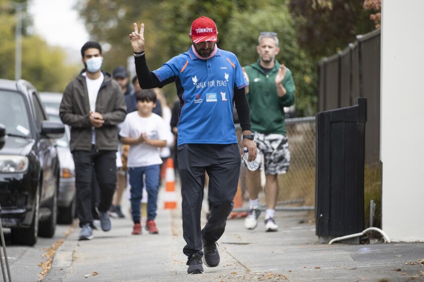 Al Noor Mosque shooting survivor Temel Atacocugu gestures as he completes his walk from Dunedin to Christchurch on the third anniversary of the shootings in Christchurch, New Zealand, Tuesday, March 15, 2022. The lingering injuries from being shot nine times did not stop Atacocugu from completing a two-week walk and bike ride for peace on Tuesday, the third anniversary of a gunman's slaughter of 51 Muslim worshippers. (George Heard/New Zealand Herald via AP)